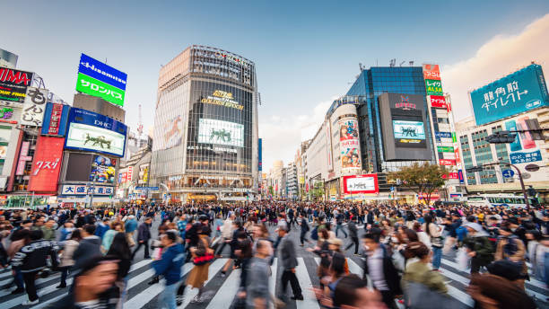 Panorama Busy Crowded Tokyo Shibuya Crossing Japan Panorama Shot of People crossing the crowded famous Shibuya Crossing in Downtown Tokyo, illuminated Shibuya Buildings with billboards in the background. Twilight light, close to sunset. Shibuya Crossing, Shibuya Ward, Tokyo, Japan, Asia. commuter photos stock pictures, royalty-free photos & images