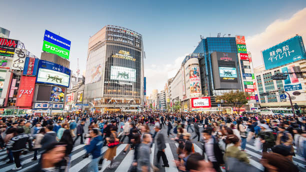 Panorama Busy Crowded Tokyo Shibuya Crossing Japan Panorama Shot of People crossing the crowded famous Shibuya Crossing in Downtown Tokyo, illuminated Shibuya Buildings with billboards in the background. Twilight light, close to sunset. Shibuya Crossing, Shibuya Ward, Tokyo, Japan, Asia. tokyo crowds on the famous shibuya crossing japan stock pictures, royalty-free photos & images