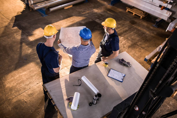 istock Above view of manager and manual workers analyzing blueprints in a factory. 1142768054
