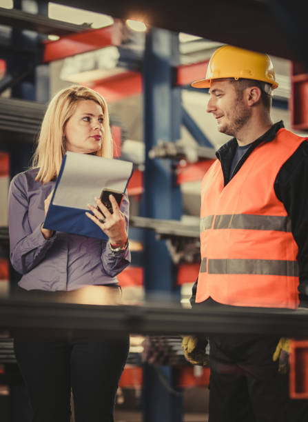 istock Manual worker and female manager talking while working on paperwork in steel mill. 1142768209