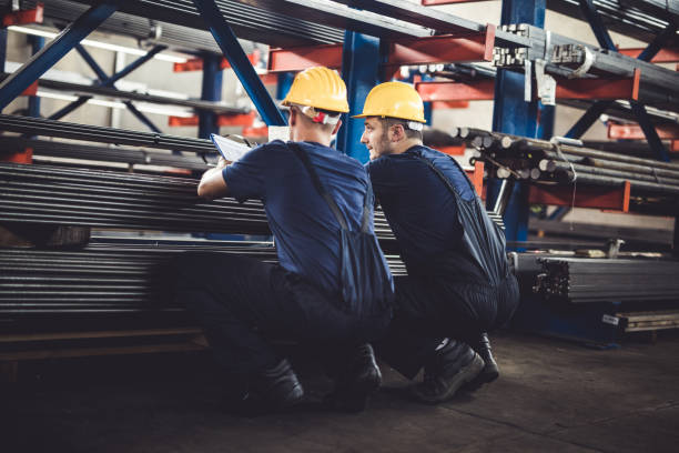 istock Back view of manual workers cooperating while reading reports in a warehouse. 1142768950