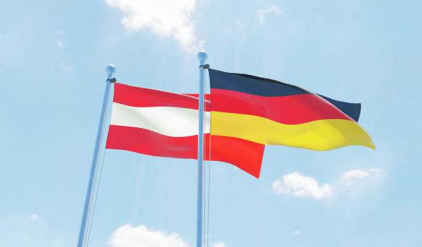istock Austria and Germany, two flags waving against blue sky 1142769203