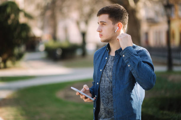 Young man use phone and wireless headphones and print message in social network.