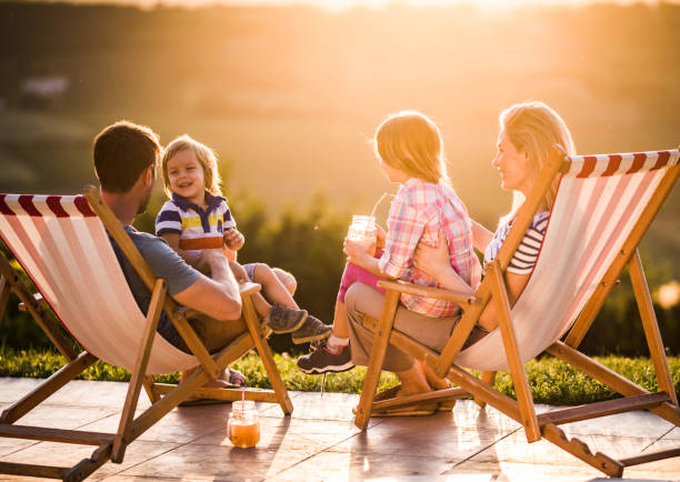 istock Happy family talking in deck chairs at sunset. 1142773601