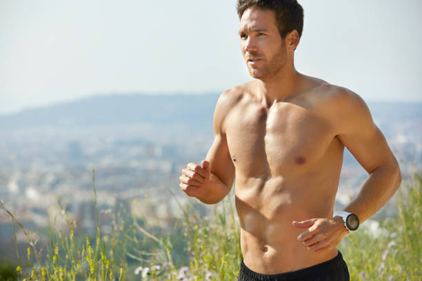 uomo a torso aperto determinato che corre al parco in estate - a petto nudo foto e immagini stock