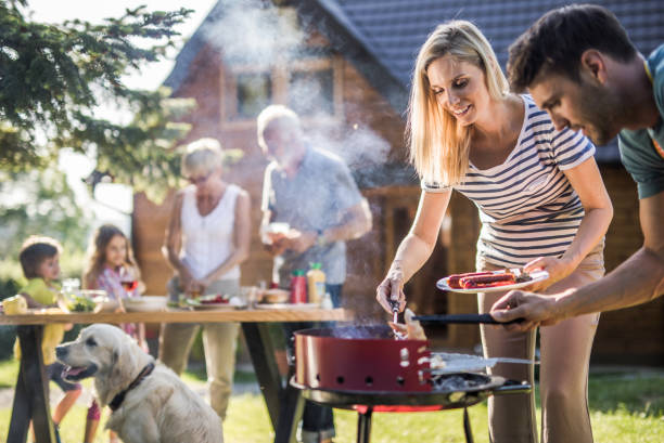 happy extended family preparing barbecue in the backyard. - picnic family barbecue social gathering imagens e fotografias de stock