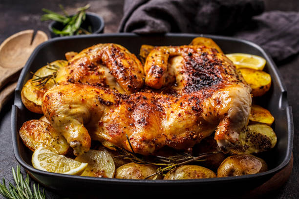 istock Roasted whole chicken with potatoes in a grill pan, dark background. 1142790578