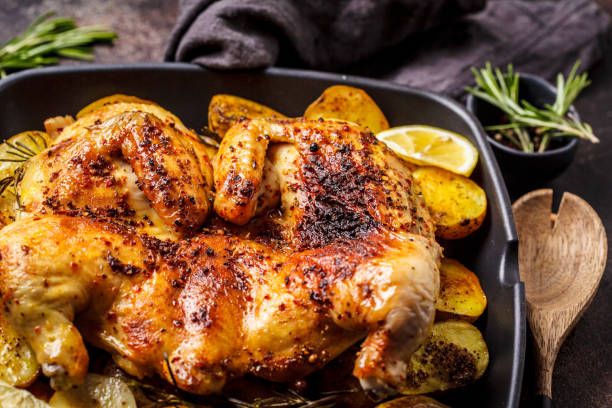 istock Roasted whole chicken with potatoes in a grill pan, dark background. 1142790590