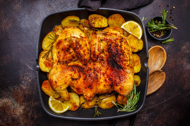 istock Roasted whole chicken with potatoes in a grill pan, dark background. 1142790612