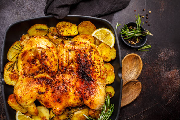 istock Roasted whole chicken with potatoes in a grill pan, dark background. 1142790630