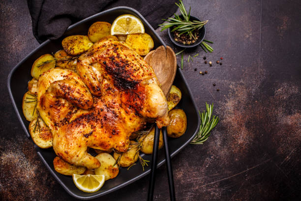 istock Roasted whole chicken with potatoes in a grill pan, copy space, dark background. 1142790648