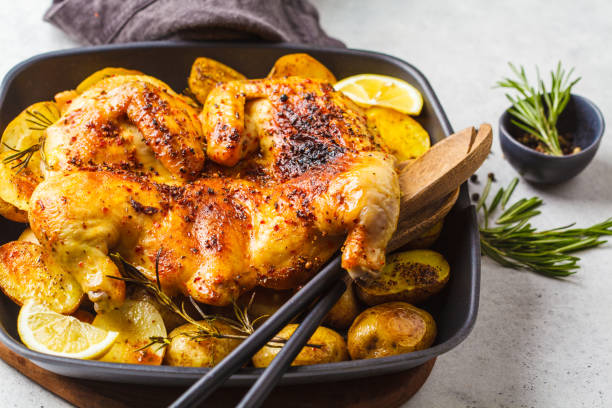 istock Fried whole tabaka chicken with potatoes in a grill pan, top view, white background. 1142790734