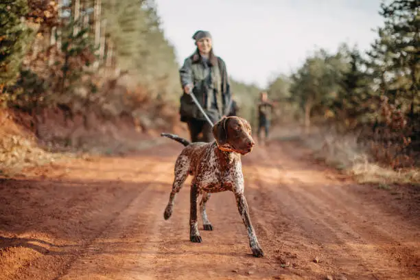 Women holding gun and leading with dog