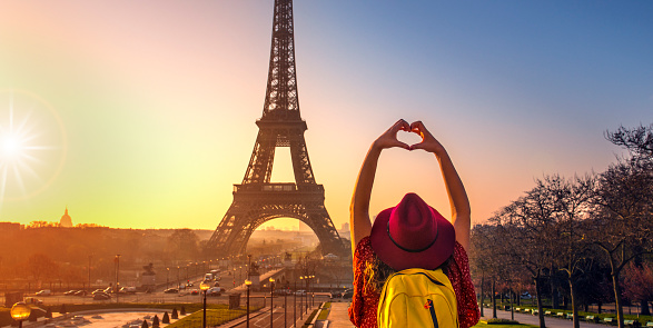 Beautiful young woman making heart shape  at Eiffel Tower, Paris.
