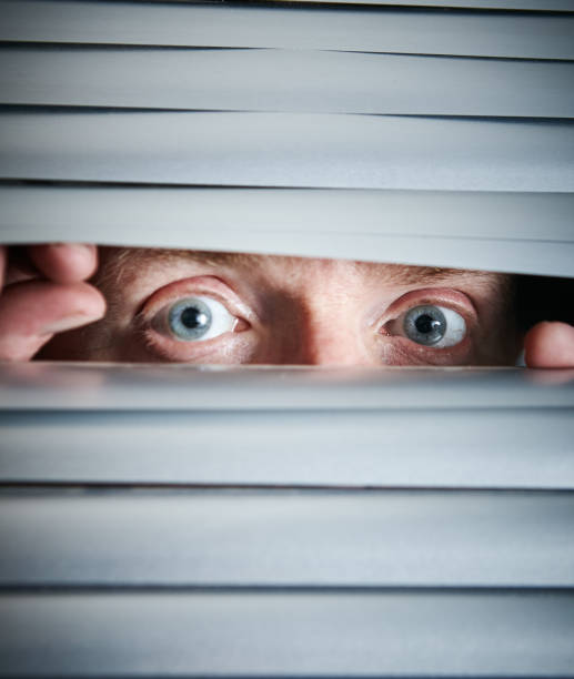 istock Nervous male eyes peer through venetian blind 1142800450