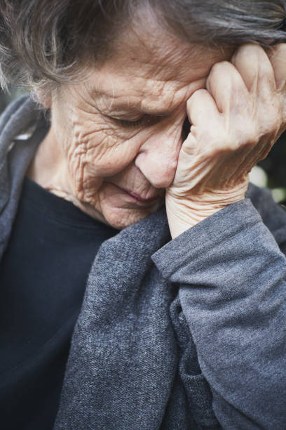 A crying elderly woman covering her face