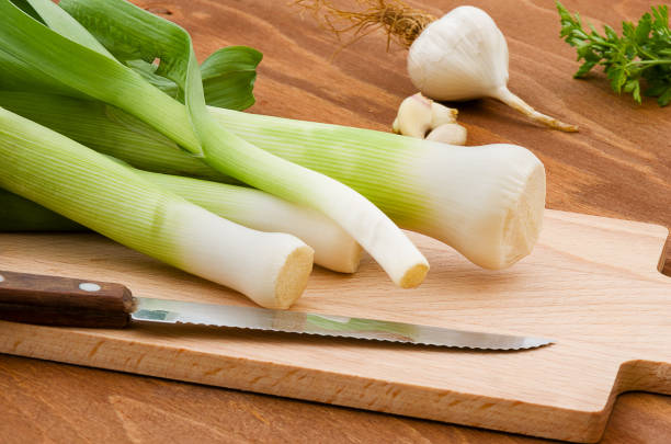 istock Leeks cut into slices on wooden plank on wooden background. 1142802064