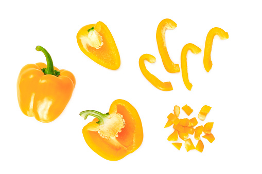 yellow bell pepper cut half into pieces on white background, top view.