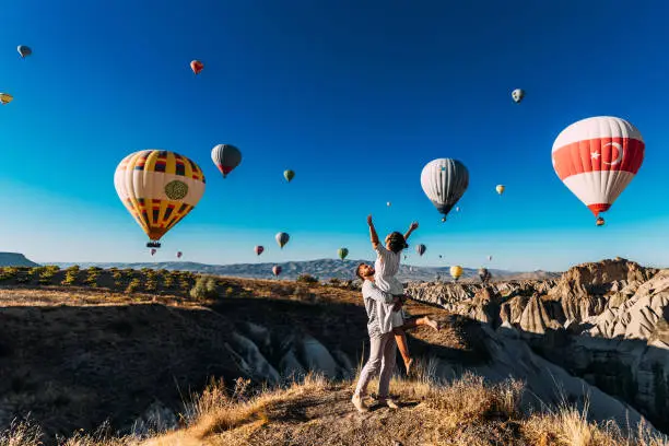 Wedding travel. Honeymoon trip. Couple in love among balloons. A guy proposes to a girl. Couple in love in Cappadocia. Couple in Turkey.  Man and woman traveling. Flying on balloons. Tourists