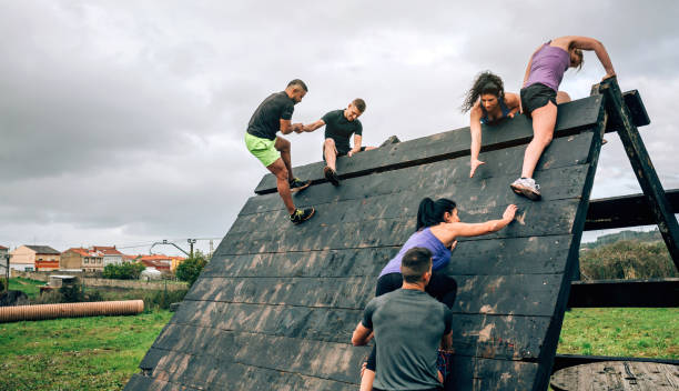Participants in obstacle course climbing pyramid obstacle Group of participants in an obstacle course climbing a pyramid obstacle obstacle course stock pictures, royalty-free photos & images