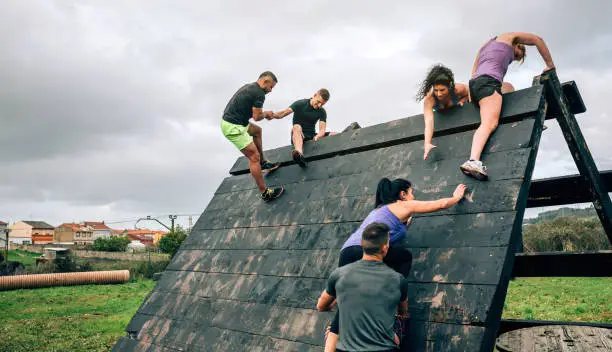 Group of participants in an obstacle course climbing a pyramid obstacle