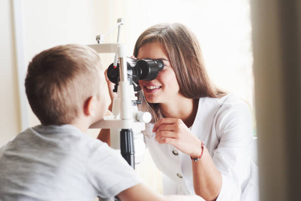 istock Smiling during the process. Little boy have test for his eyes with special optical apparatus by female doctor 1142803438