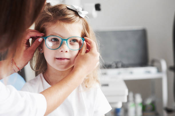 nueva mirada. doctor dándole a la niña nuevas gafas para su visión - gafas fotografías e imágenes de stock