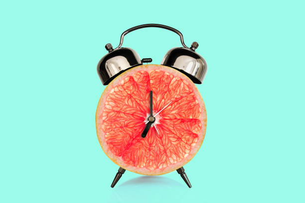 istock Grapefruit slice on alarm clock, blue pastel background. fruit and vitamins diet at breakfast nutrition concept 1142803676