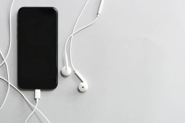 istock Mobile with black screen and earphone on white table with free copy space. 1142806623