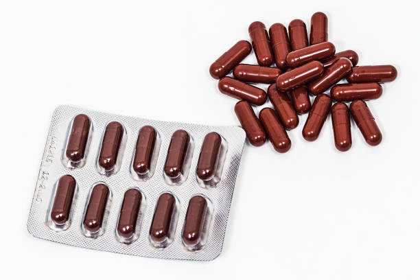 istock medicinal brown capsules in blister and without it on white background. 1142807162