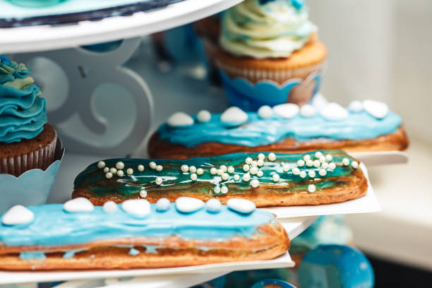 istock delicious eclairs with turquoise cream and cupcakes close-up on festive table. 1142807244