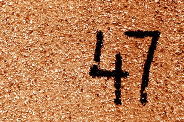 istock Number 47 on cement wall in stencil in orange tone. 1142810595