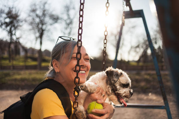 istock Senior woman sitting on swing with dog 1142818264