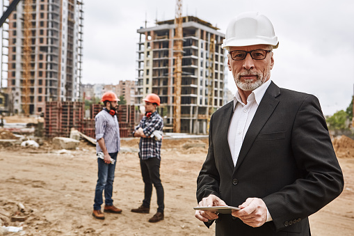 Portrait of male construction worker posing for a shot while his team is working in the background