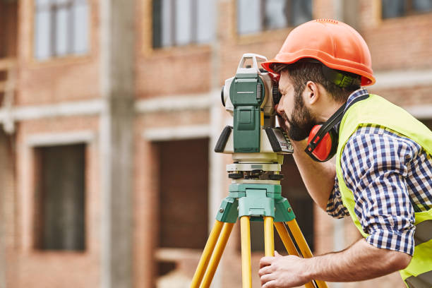 prace geodezyjne. inżynier geodeta w zużyciu ochronnym i czerwonym kasku przy użyciu sprzętu geodezyjnego na placu budowy. profesjonalny sprzęt. - azimuth zdjęcia i obrazy z banku zdjęć