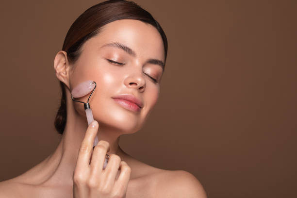 istock Pleased woman relaxing with rose quartz face roller 1142821476
