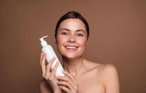istock Woman with bare shoulders holding white bottle with dispenser 1142821484