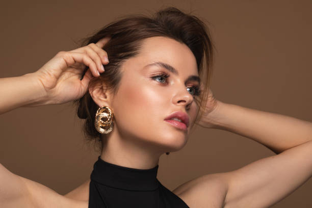 attraktive frau posiert in abendkleidung mit goldenen ohrringen - gold earrings stock-fotos und bilder