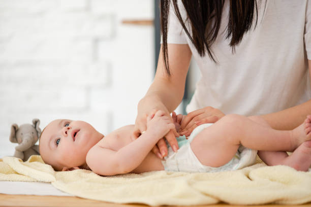 istock Young mother changing diaper her baby 1142822998