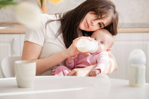 istock Feeding newborn with formula in a bottle in kitchen. 1142823207