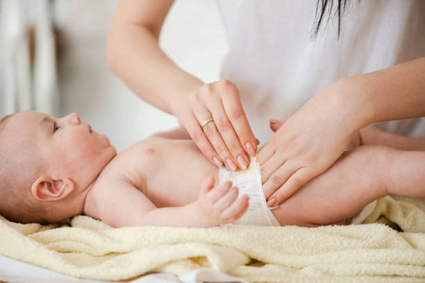 mutter fixiert windel-klettverschluss auf baby-taille - verwöhnen stock-fotos und bilder