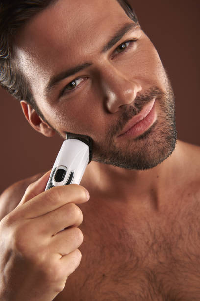istock Close up of smiling young guy shaving himself 1142825586