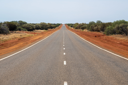 Long straight road leading through the dry Australian Bush land