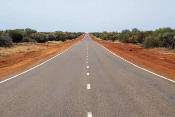 Long straight road leading through the dry Australian Bush land stock photo