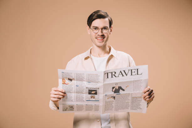istock cheerful man reading travel newspaper isolated on beige 1142826794