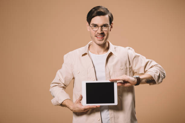 istock smiling man in glasses holding digital tablet with blank screen isolated on beige 1142826811