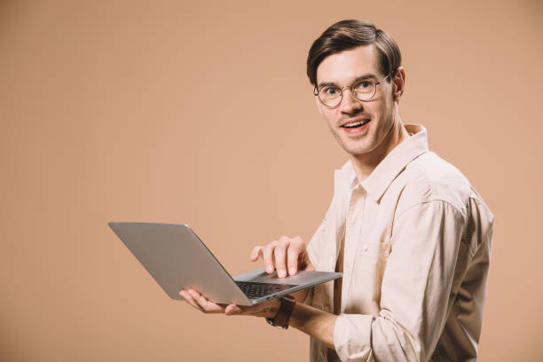istock handsome man in glasses using laptop isolated on beige 1142826832