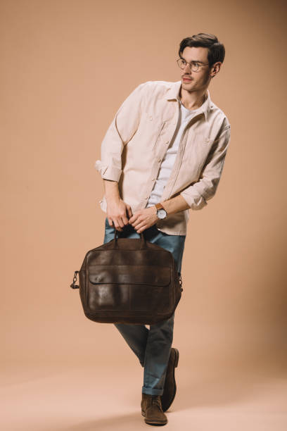 istock handsome man in glasses holding bag on beige background 1142826855
