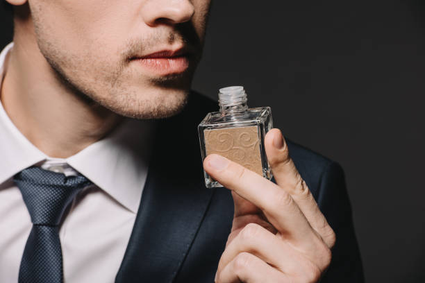 istock cropped view of man smelling perfume isolated on black 1142827647