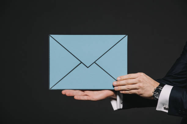 istock cropped view of man holding blue envelope isolated on black 1142827690
